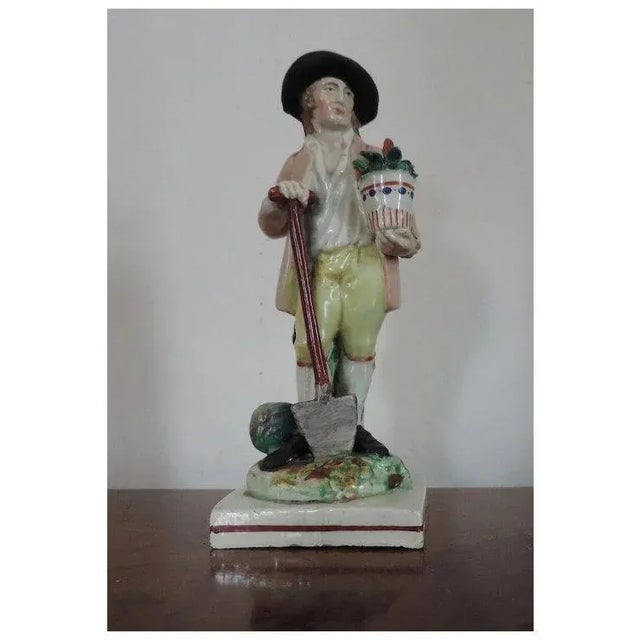 Antique 18th c. Staffordshire pearlware figure of a gardener resting on his spade with melons at his feet and holding a...