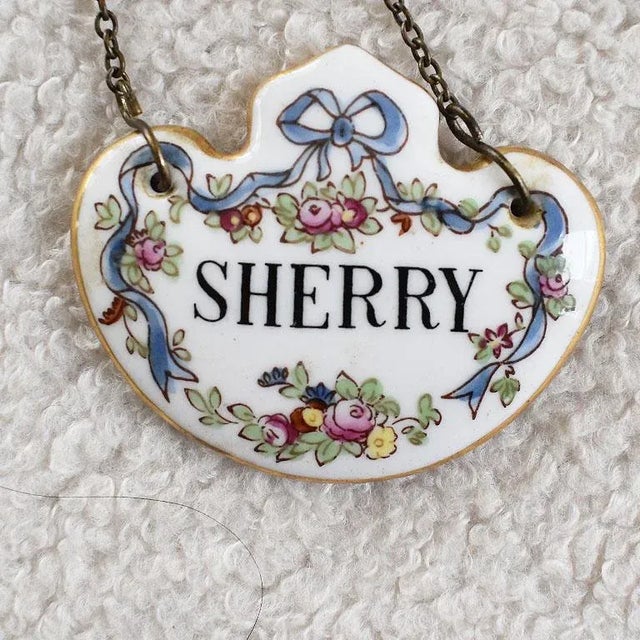A set of three antique liquor bottle decanter tags. Each tag is created from fine porcelain in a medallion shape. On a...