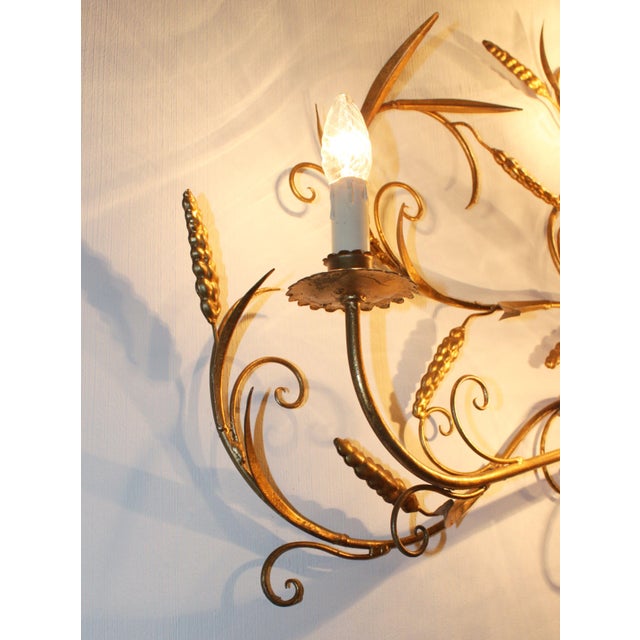 An imposing wall sconce by Hans Kögl in gilded metal, featuring eight lights with bobeches and an abundant, elegant wheat-...
