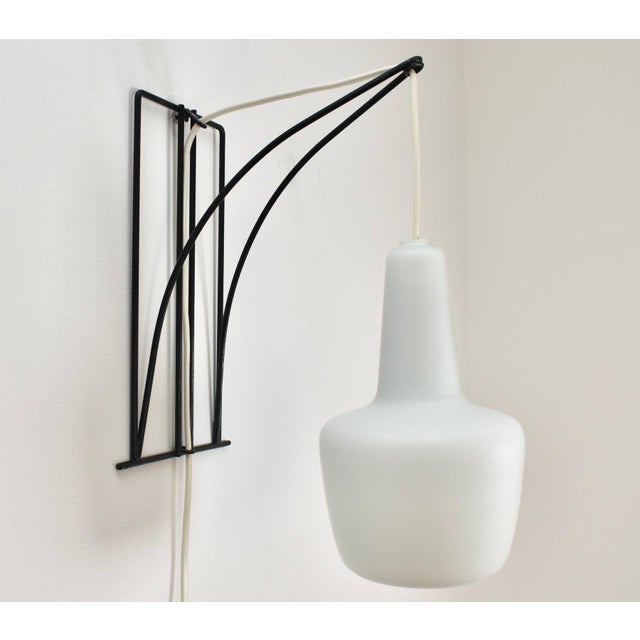 Modernist wall sconce made from black painted wire metal and a satined milk glass lampshade. Likely designed by Louis...