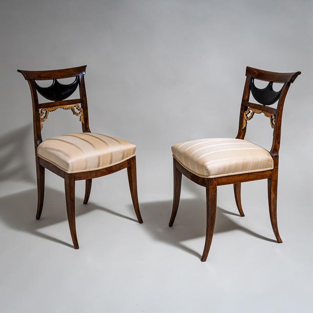 Pair of Biedermeier chairs with upholstered seats and stained beechwood frames. The unusually designed backrests feature...