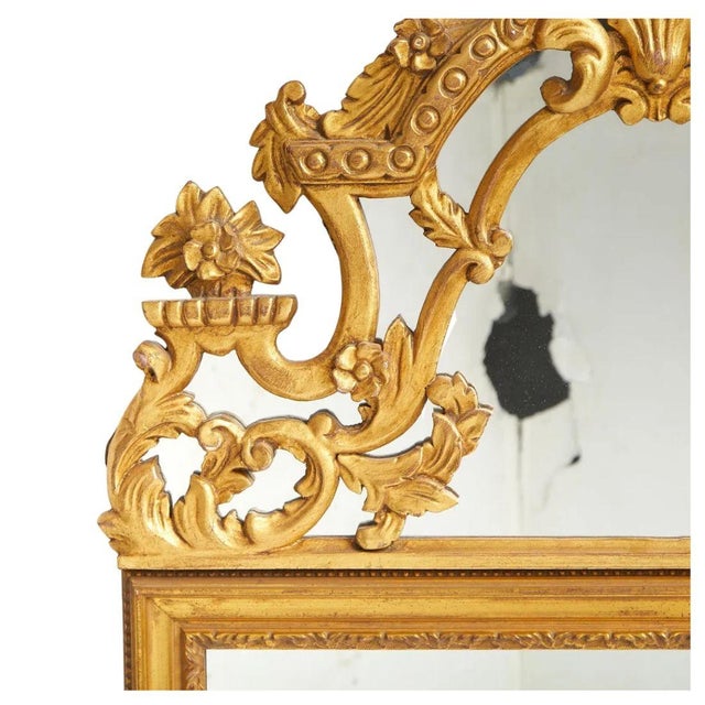 A pair of Louis XV inspired giltwood rococo rectangular mirrors with decorative crest. The rectangular mirror plates are...