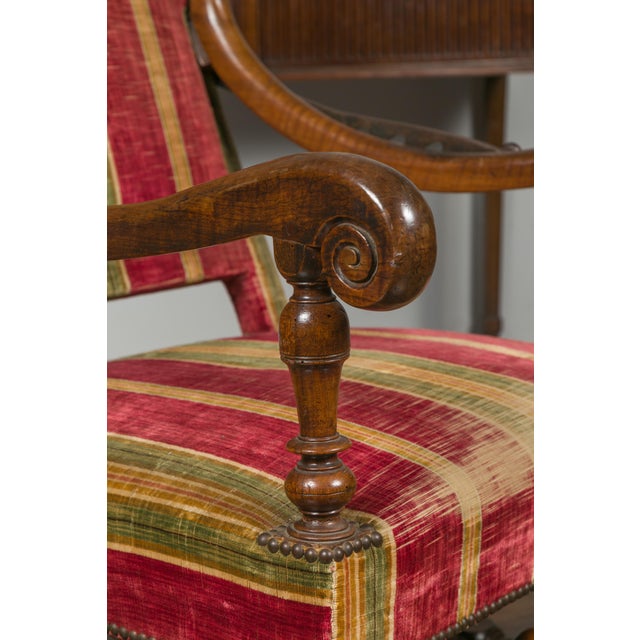 A French Louis XIV style walnut reclining armchair from the 19th century, with large scrolling arms and turned base....