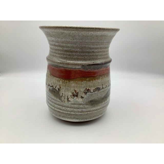 Vintage signed stoneware glazed with a vibrant red/orange band. The vase also has white, antique white, gray, tan and...