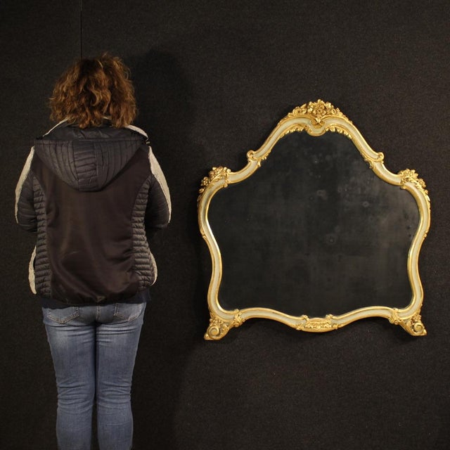 Mid-20th-century Italian mirror. Carved, lacquered, and gilded wood furniture in an antique style, it features beautiful...