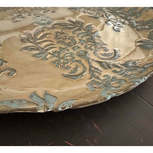 Monumental mid-century brass charger with raised verdigris damask relief. Measuring 18 inches in diameter, this piece...