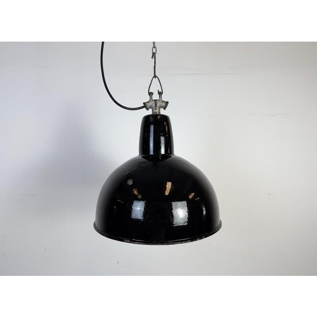 Industrial black enamel pendant light made in former Czechoslovakia during the 1950s. White enamel inside the shade. Cast...
