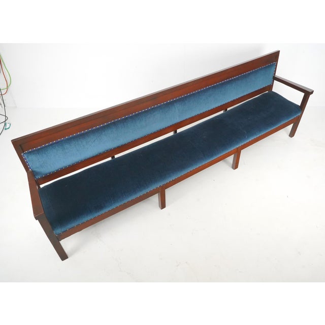 Traditional style settee bench with a dark stained walnut frame and upholstered in deep blue velvet fabric lined with...