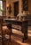 This is a dark wood writing table featuring a rectangular overhanging top above two frieze drawers fitted with round...