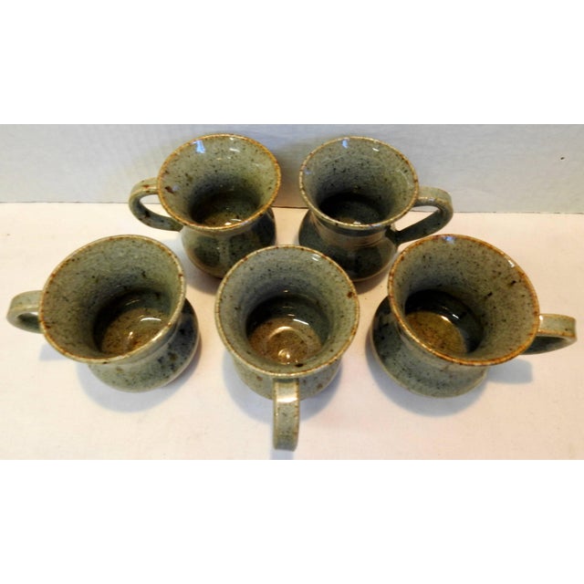 Neutral tones with brown decorate this set of five hand thrown stoneware mugs. They are all the same style but each one is...