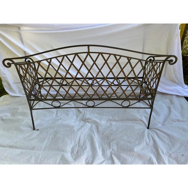 A single vintage outdoor iron sofa or bench featuring a curved back, rolled arms, and lattice style sides and back. Seat...