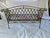 A single vintage outdoor iron sofa or bench featuring a curved back, rolled arms, and lattice style sides and back. Seat...