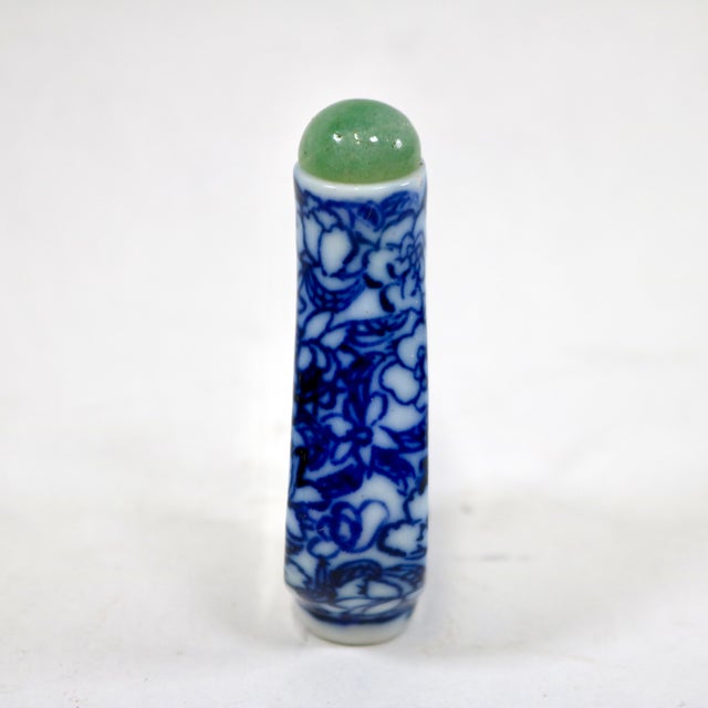 The vintage blue and white floral Chinese snuff bottle with a green stone top is a handmade collectible from China....