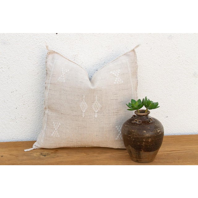Subtle star and cross motifs appear in soft tone-on-tone stitching across this handcrafted Moroccan cactus silk pillow,...