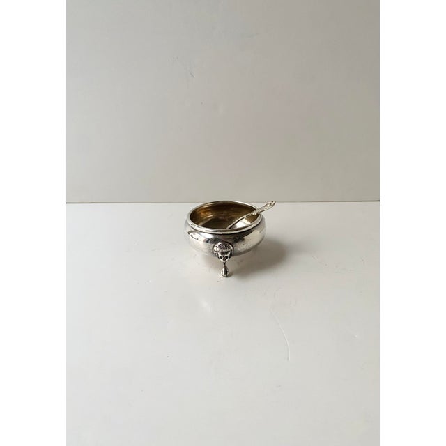 A sterling silver salt cellar vessel and sterling silver spoon with Lion head and paw feet detail, in the Empire style,...