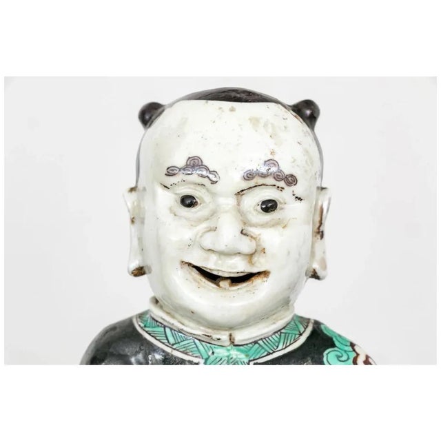 Antique Chinese famille noir porcelain figure of an attendant. With his hair pulled back and eyebrows painted in cloud...