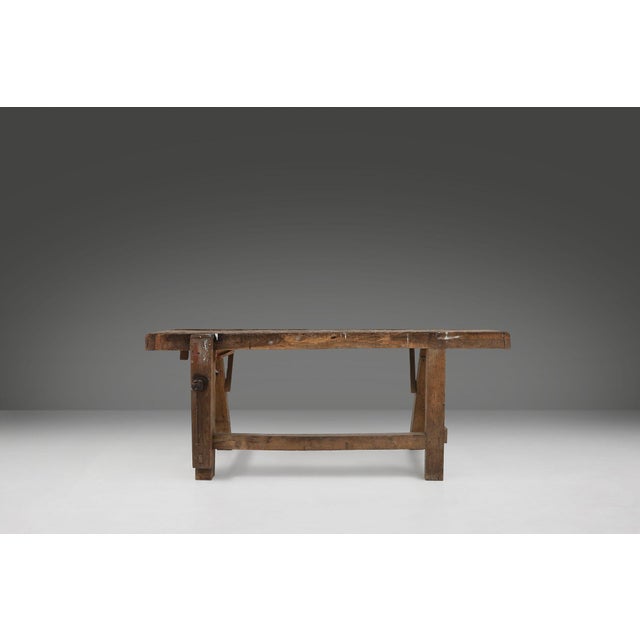 A powerful example of early industrial Belgian craftsmanship, this solid oak workbench from around 1900 carries the...
