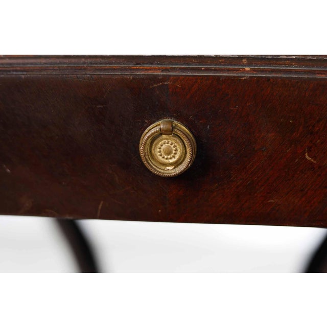 Antique sculptural side table. Mahogany with brass lions heads and other details. Embossed leather top is distressed in...