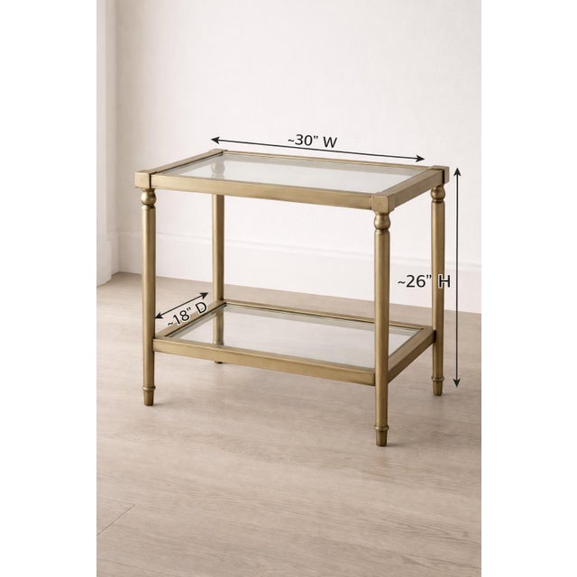 Elegant vintage Hollywood Regency side table with a brass-toned frame and two fitted glass shelves. A refined accent piece...