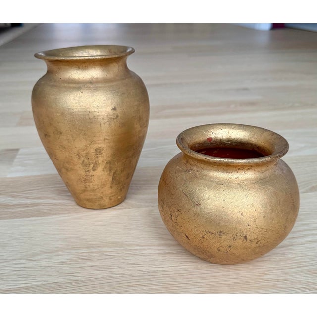 Striking pair of vintage Italian decorative vases crafted in terracotta with hand-applied gold leaf, each formed in a...