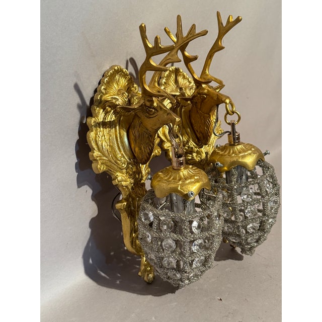 A striking pair of late 20th-century French Louis XVI-style gilt bronze wall sconces, designed with sculptural deer head...