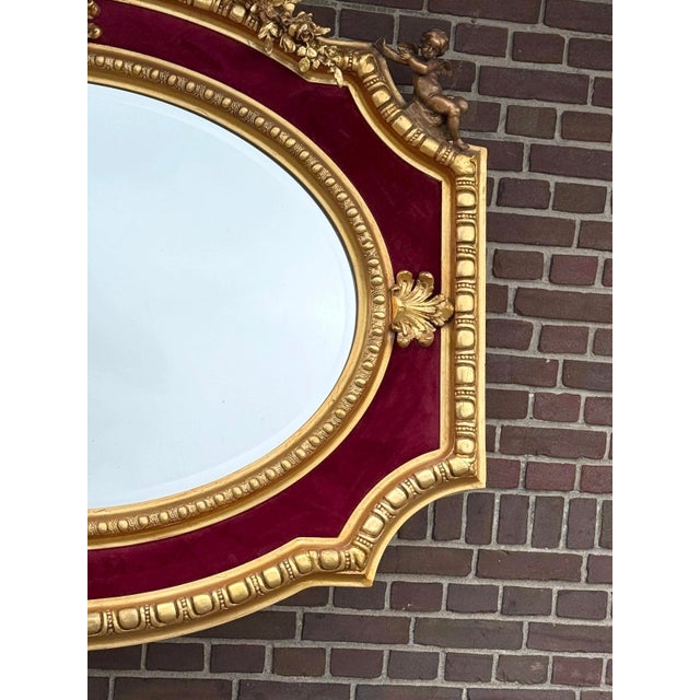 An elegant 1970 French Louis XVI–style wall mirror, crafted with a richly carved wooden frame, warm antique gold finish,...