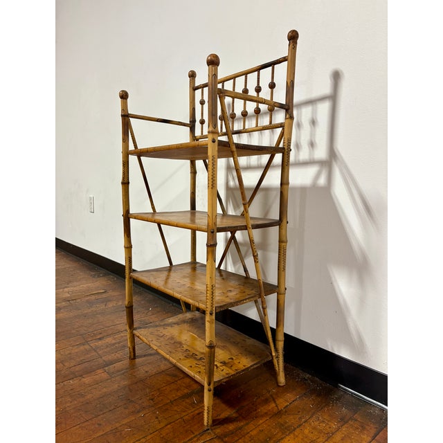 Antique English bamboo etagere featuring a scorched or burnt bamboo frame and four shelves. In the style of Victorian or...