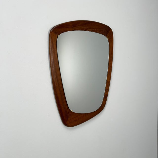 Rare organically shaped wall mirror with a thick frame made of solid teak wood.