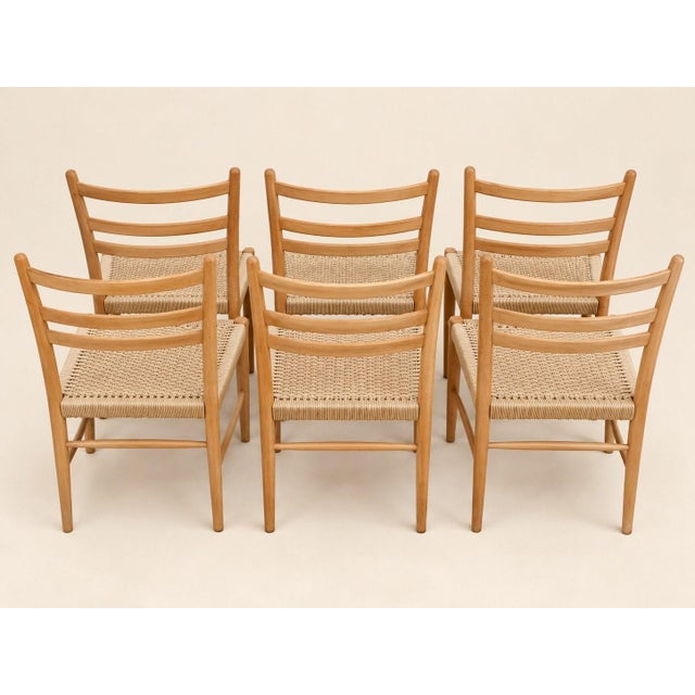 A set of six dining chairs that gracefully embody the elegance of 1960s scandinavian design. their solid wood frames—oak...