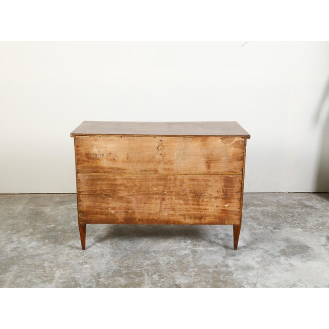 An Italian neoclassical period fruitwood commode from the early 19th century, with four drawers and marquetry décor....