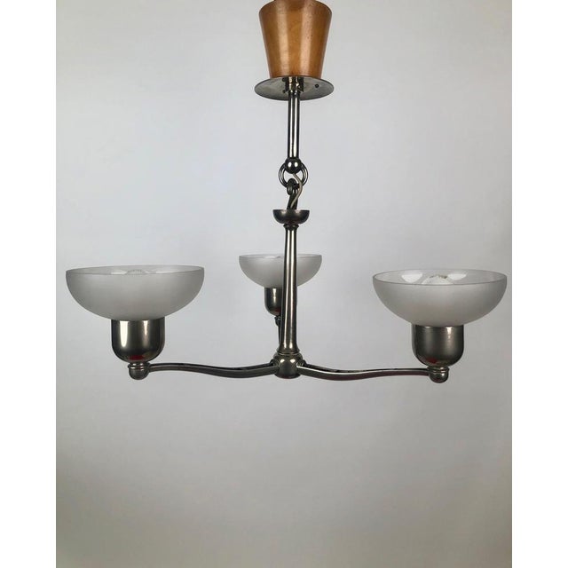 A functionalist three arm chandler from 1930, Austria. The metal parts are made from cast aluminium with an unusual wooden...