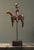 A vintage hand carved folk art sculpture depicting a soldier seated atop a horse, mounted on a rod and stained wooden...