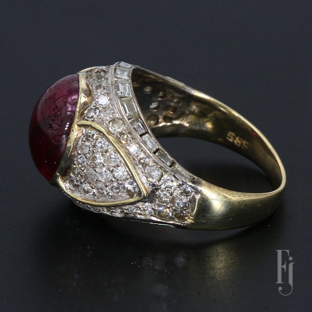 Here is a 14k Yellow Gold Cocktail Ring featuring a 9.0ct Oval Ruby Cabochon Center stone, accented by White Diamonds....