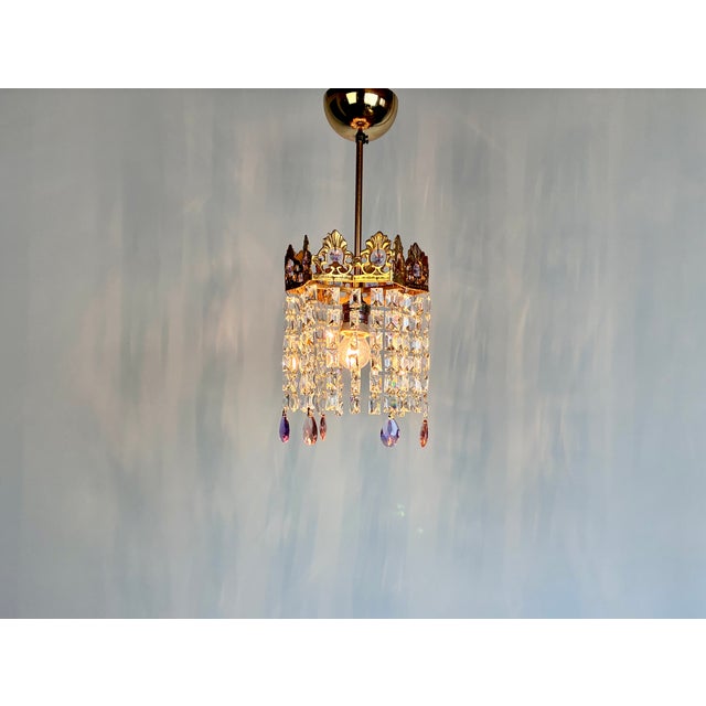 Vintage brass mini chandelier featuring original pink and purple crystal prisms. Despite its compact size, this chandelier...