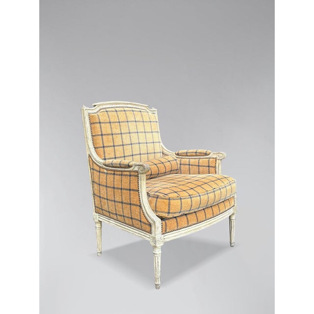 A late 19th-century French Louis XVI style carved white painted bergère armchair. The carved painted frame features a...