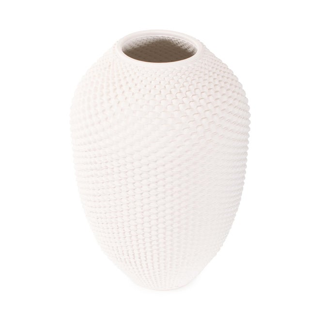 Featuring an intricate knitted-like texture reminiscent of soft woven fibers, this elongated ceramic silhouette brings...