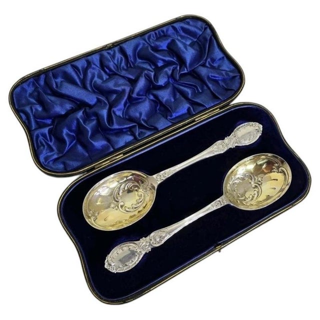 A fine pair of antique sterling silver serving spoons dating to 1909, displaying an elegant Neoclassical design and richly...