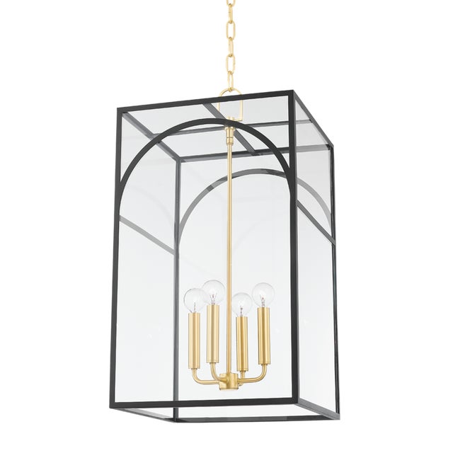 Like a fixture within a fixture, a series of aged brass candlesticks hang within a decorative metal cage. The arched...