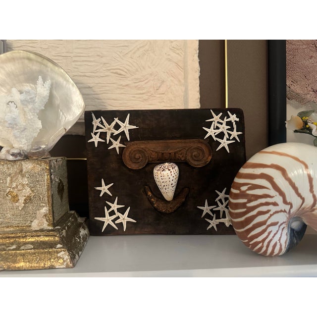 This whimsical and sculptural shell art is mounted on a vintage wooden mold, possibly once part of a furniture or...