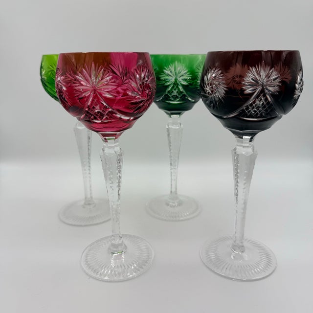 A set that feels collected rather than matched—four cut-to-clear crystal hock glasses in rich jewel tones, each catching...
