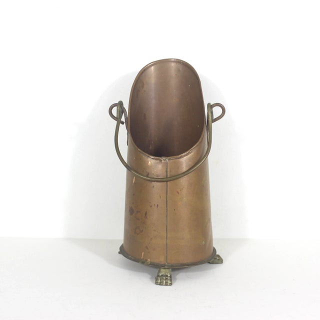 Vintage copper coal scuttle with three brass lion paw foot details, brass handle and base. Would make a lovely vase, but...