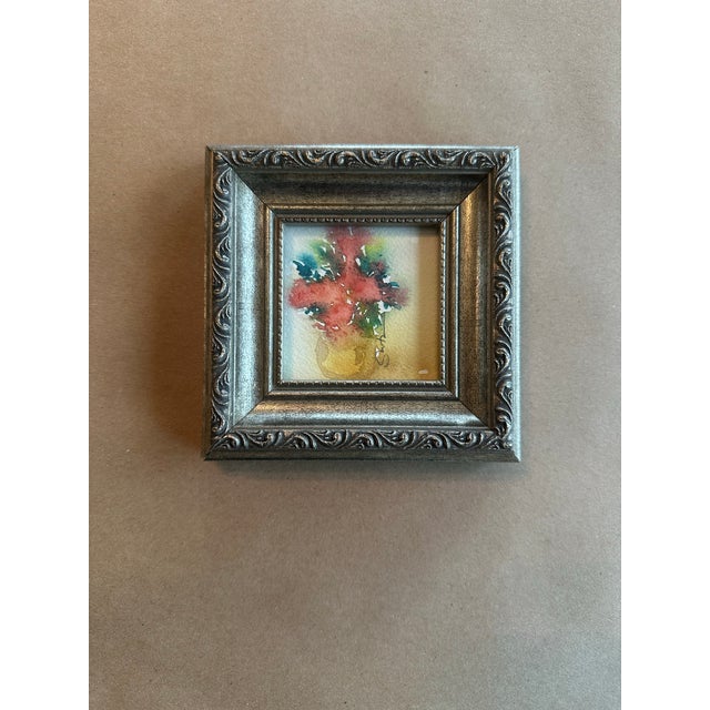 A delicate miniature botanical rendered in expressive watercolor, featuring soft crimson blossoms with touches of green...