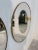 A pair of Italian round wall mirrors from the 1950s, each encircled by a slender brass frame with a graceful aged patina....