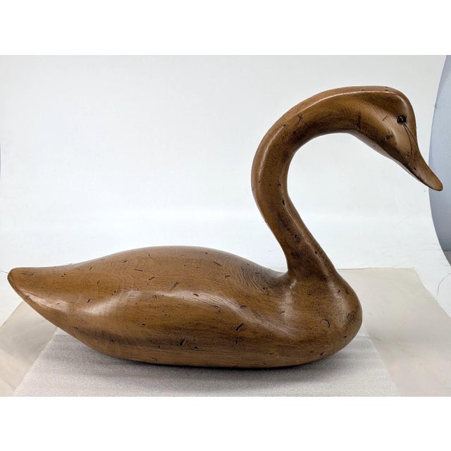 An iconic, carved-wooden decoy swan, standing at a commanding 27 inches as the main attraction, is a wondrous sculptural...