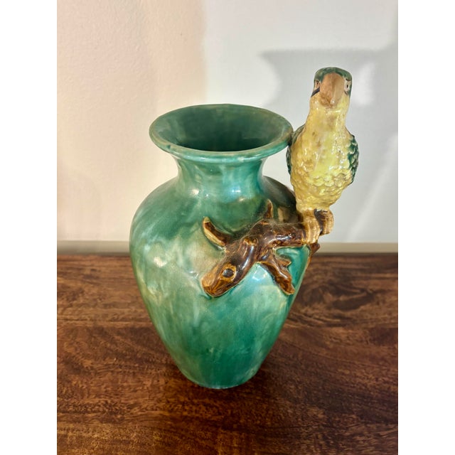 A charming 1950s Italian Majolica vase featuring a beautifully sculpted green and yellow parrot perched on a naturalistic...