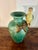 A charming 1950s Italian Majolica vase featuring a beautifully sculpted green and yellow parrot perched on a naturalistic...