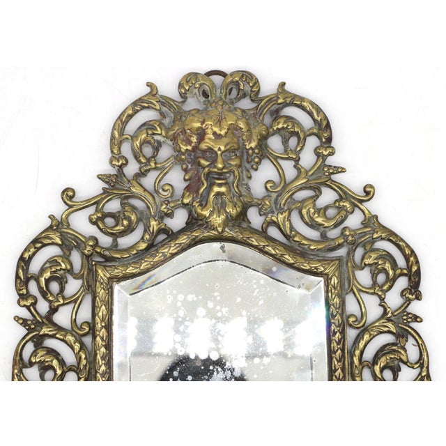 Antique Rococo Revival beveled wall mirror in cast brass. The swirling foliate designs are center pieced by Bacchus,...