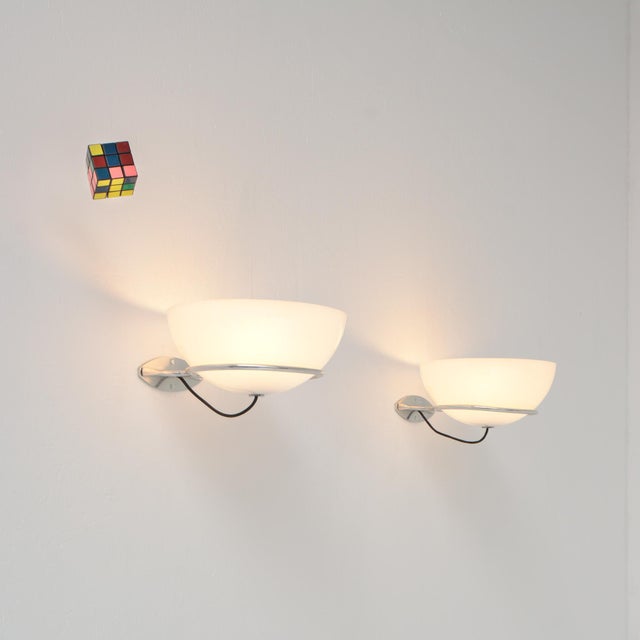 These wall lamps were designed by Gino Sarfatti for Arteluce in 1960. The 2/1 wall lamp features a ring and wall flange in...