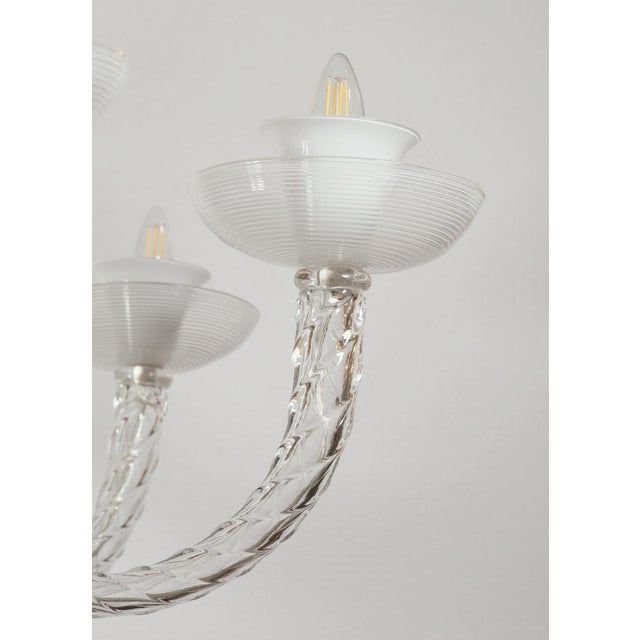 This hand-blown, Italian chandelier is an example of artisanal craftsmanship, featuring clear and white Latticino glass....