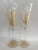 A stunning pair of hand-painted champagne flutes featuring gold feather-like designs and a golden heart accent at the...